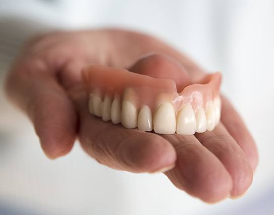 Hand holding a full removable denture