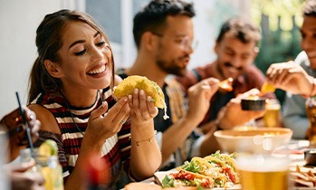 Woman smiling while eating lunch with friends at restaurant