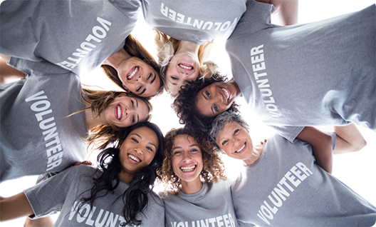 Several people in volunteer shirts putting heads together