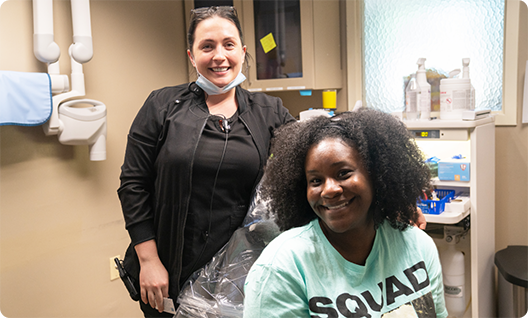 Female dentist standing behind girl in dental chair