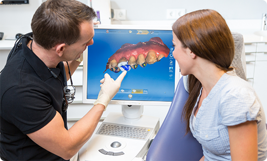 Dentist showing female patient scan of teeth