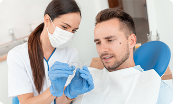 Female dentist showing male patient a clear aligner