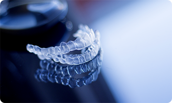 Two clear aligners sitting on a reflective surface