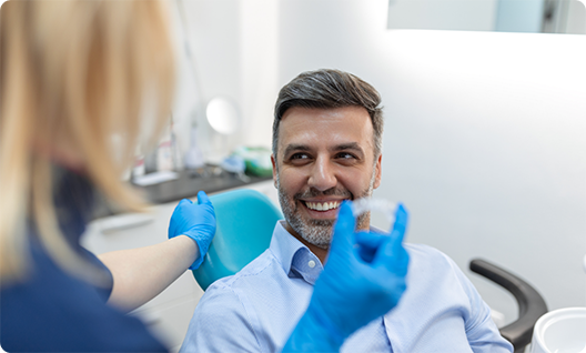 Man smiling while dentist shows him a clear aligner