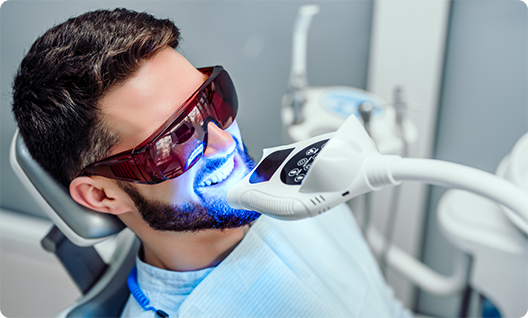 Male patient in dental chair receiving teeth whitening