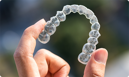 Close up of hand holding a clear aligner