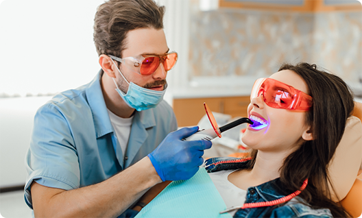 Male dental patient performing dental bonding on womans teeth