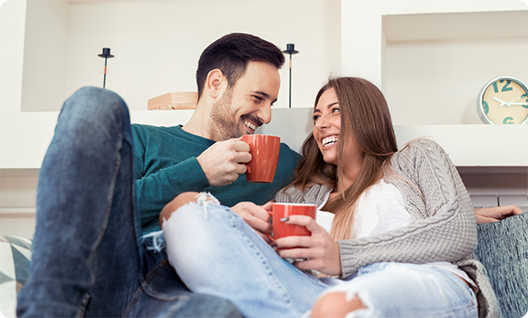 Man and woman snuggling on couch and laughing