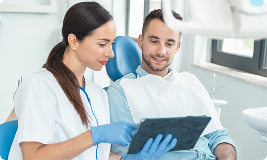 Female dentist showing male patient information on a tablet