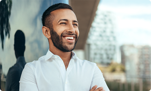 Man in white shirt smiling outside with arms folded