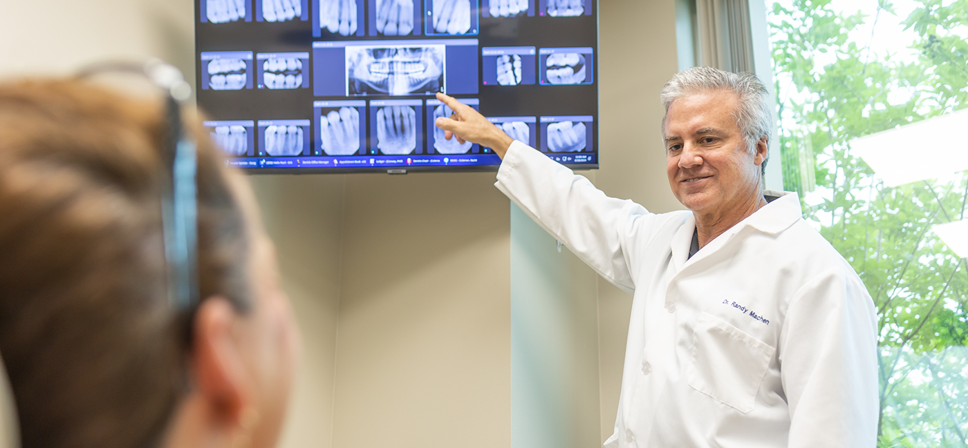 Male dentist showing patient X rays on monitor