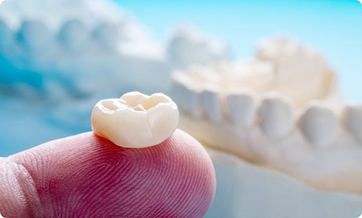 Close up of finger supporting a dental crown in Little Rock