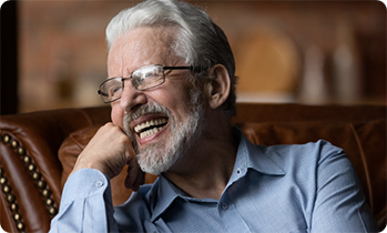 Senior man sitting on couch and smiling