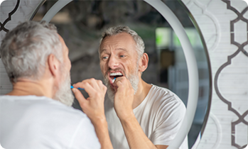 Man brushing his teeth in mirror