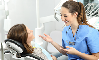 Female dentist talking to patient in chair