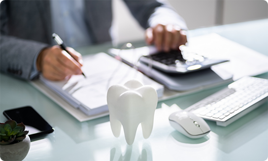 Tooth sitting on desk in front of person filling out form and using calculator