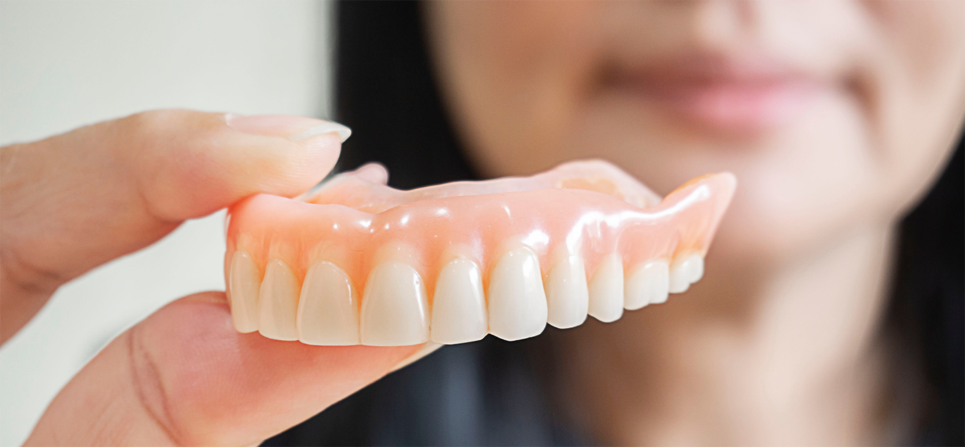 Close up of woman holding a denture in Little Rock