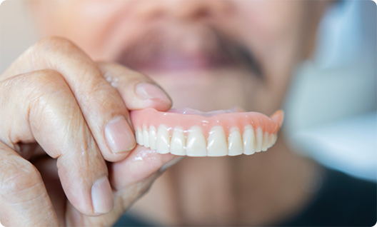 Close up of man holding a full denture