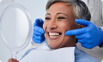 Senior woman checking smile in handheld mirror