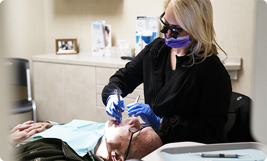 Blonde female dentist treating a male patient