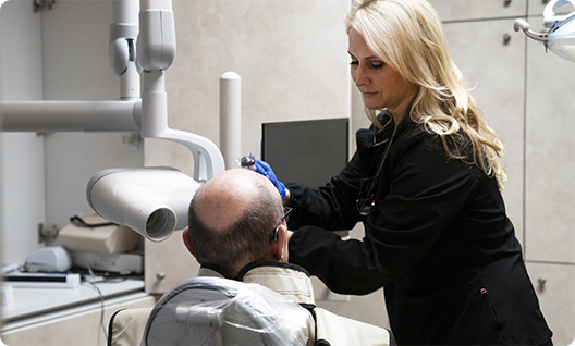 Blonde female dentist treating a male patient