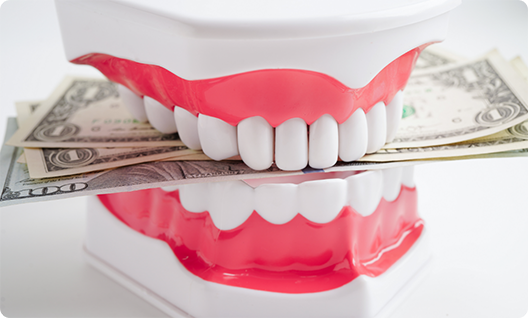 Dentures biting down on a wad of bills