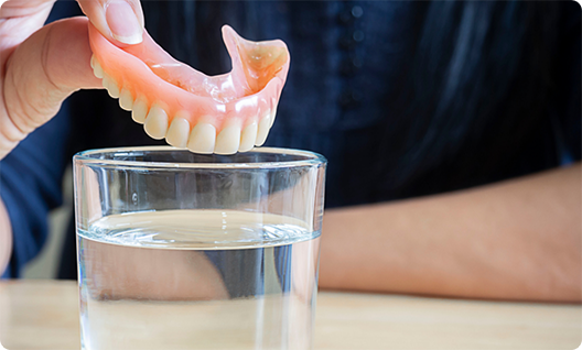 Man putting denture in a glass of water