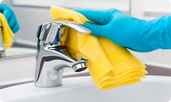 Gloved hand wiping down a faucet