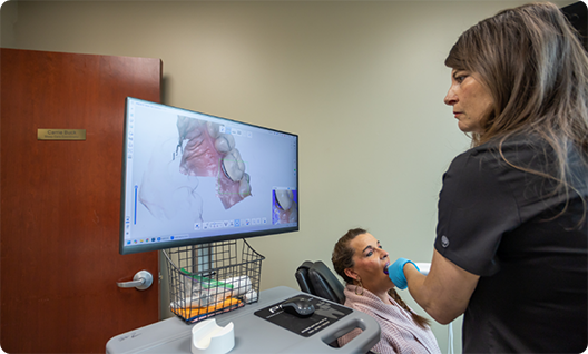 Womman scanning patients mouth and looking at monitor