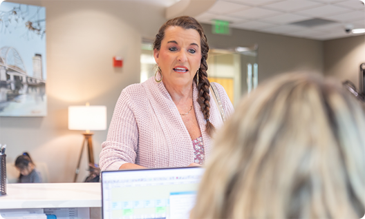 Woman talking to another woman sitting at a computer