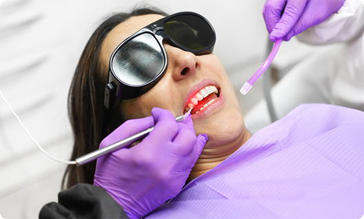 Female patient smiling with dentist holding laser and another device