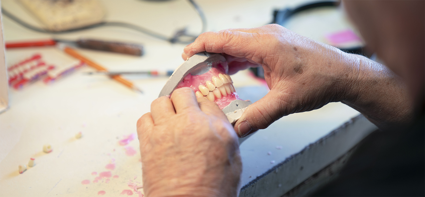 Dentures in process of being made being held by prosthodontist