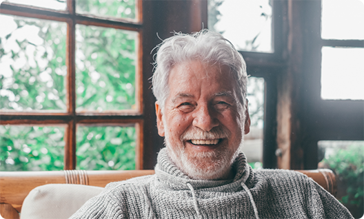 Man in grey sweater smiling while sitting in cabin