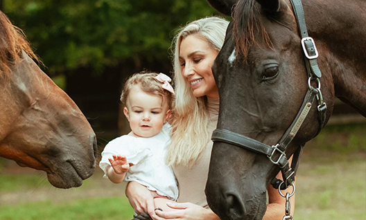 Woman holding baby with two horses