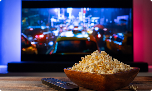 Bowl of popcorn on table in front of TV playing movie