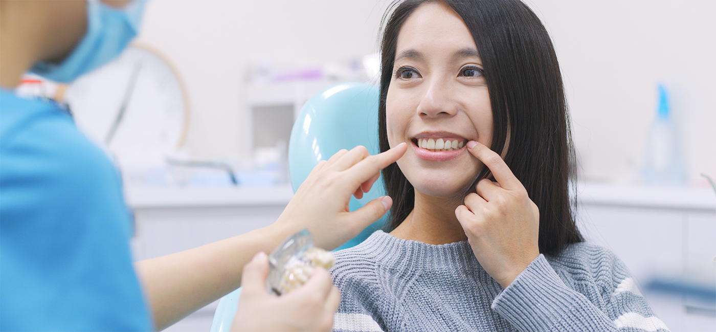 Close up of woman in dental chair pointing to smile