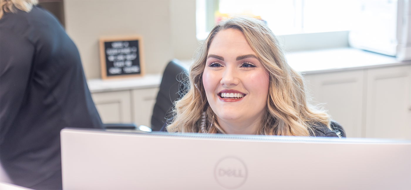 Woman sitting in front of computer monitor and smiling