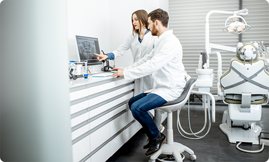 Male and female dentist looking at a monitor