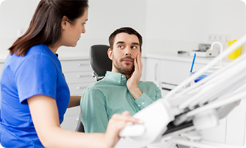 Female dentist talking to patient with tooth pain