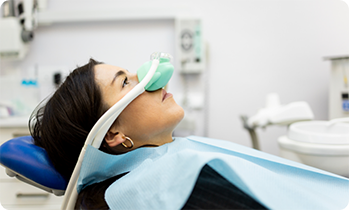 Woman sitting back in chair with mask over nose for nitrous oxide sedation