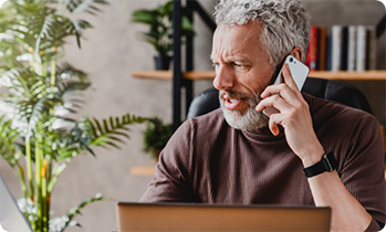 Man at laptop speaking on phone