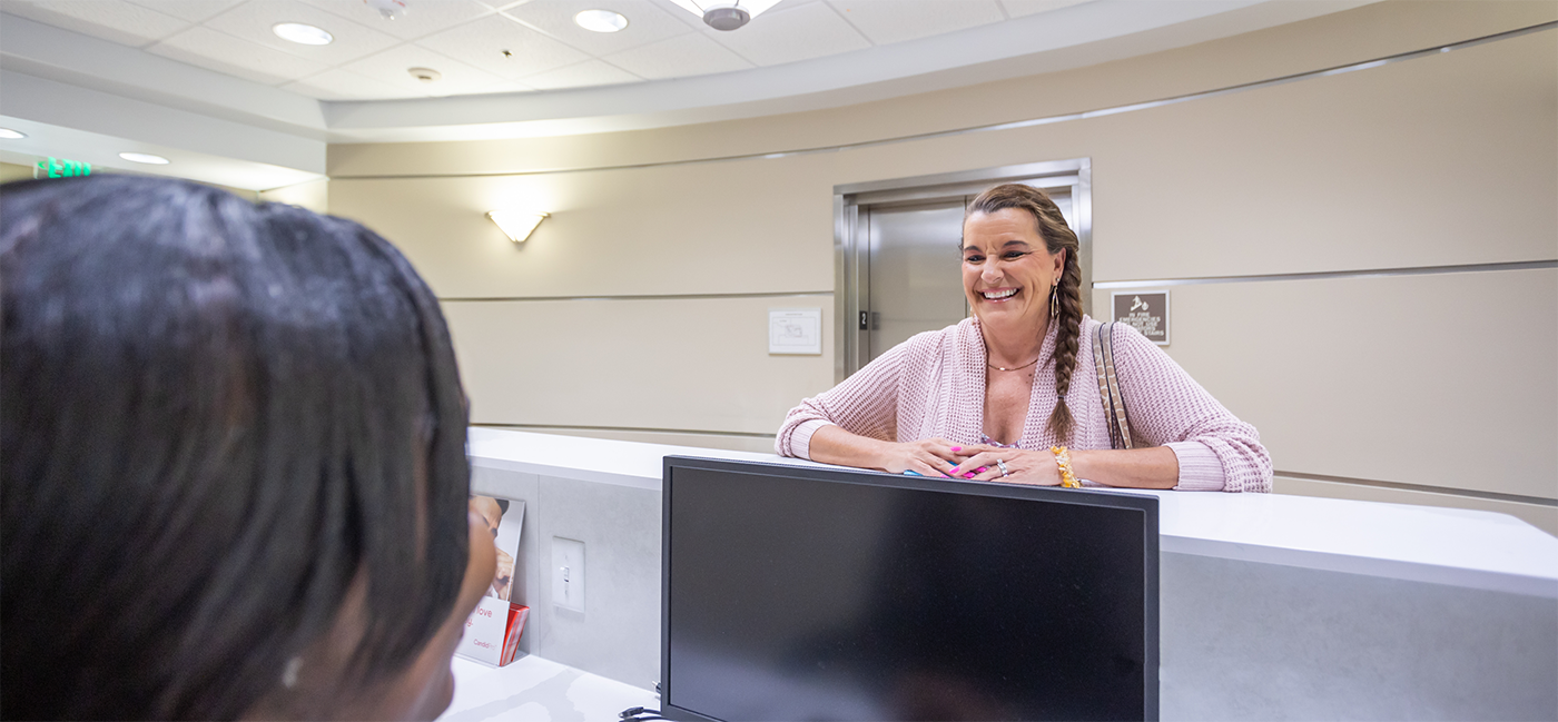 Woman laughing and speaking to team member at front desk