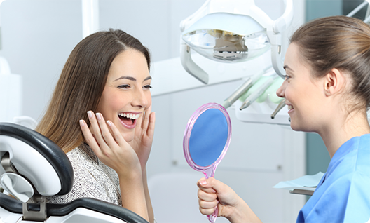 Dentist showing delighted patient smiling in mirror