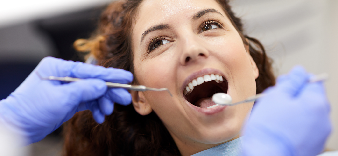 Woman holding mouth open for dental examination