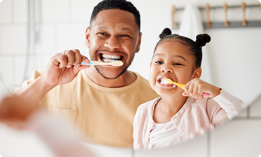 Man and daughter brushing teeth in mirror