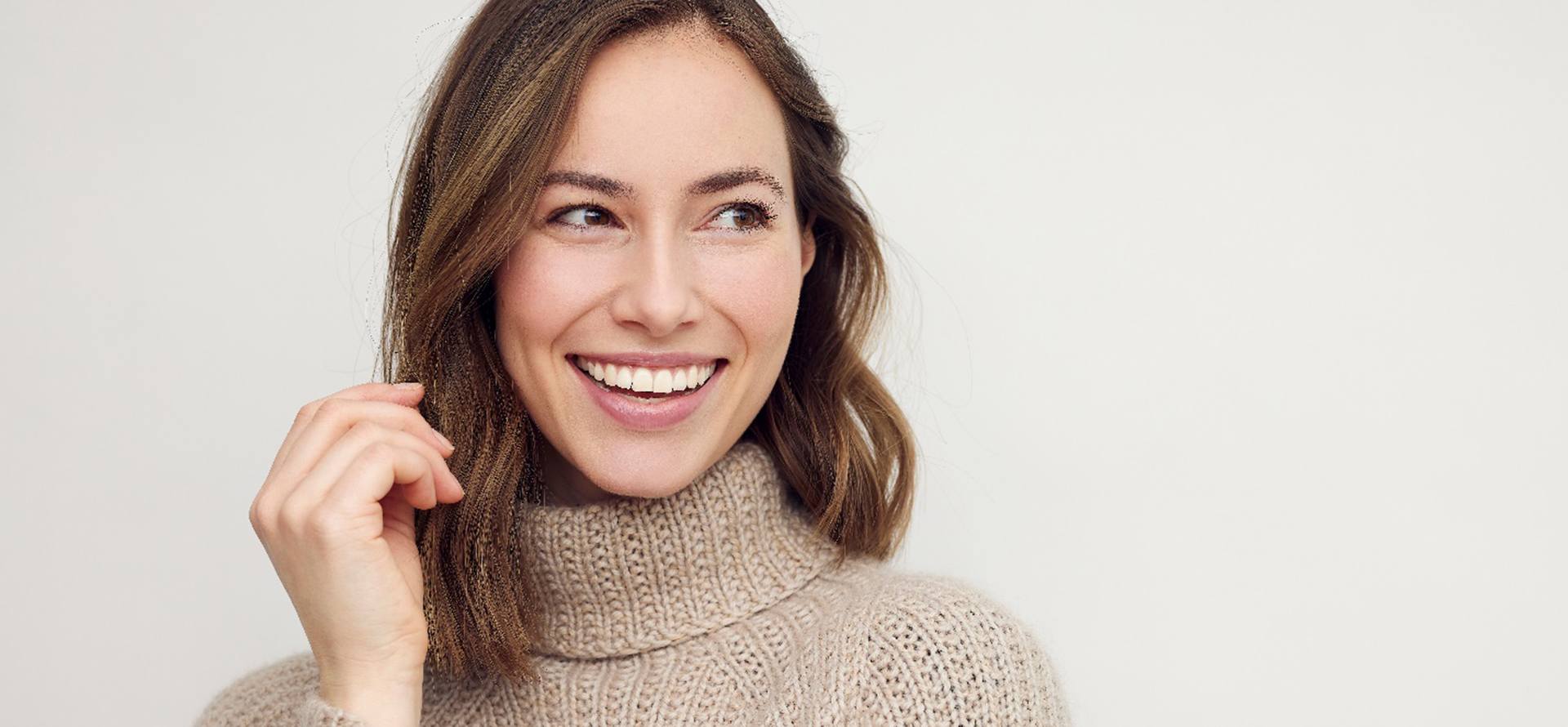 Woman in tan, turtleneck sweater smiling