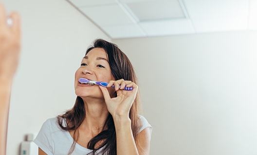 Closeup of woman brushing her teeth in bathroom